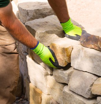 Handwerker beim Bau einer Trockenmauer aus Sandstein